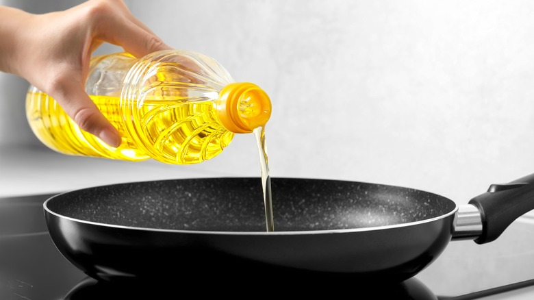 hand pouring oil into a pan