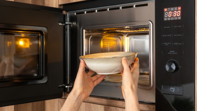 hands putting bowl in microwave