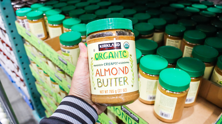 Handheld jar of Kirkland Signature Creamy Almond Butter