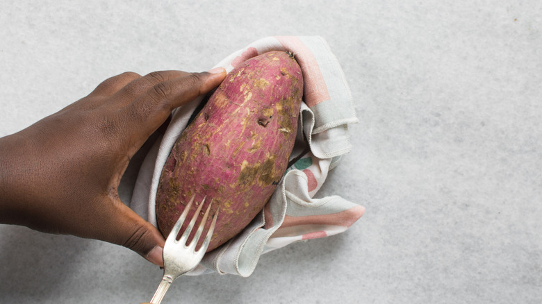 Person poking holes in a sweet potato