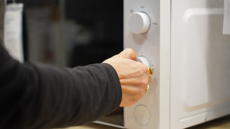 Person adjusting the settings on a microwave