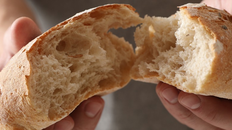 person splitting bread loaf in half