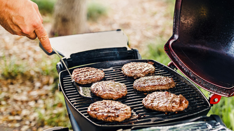 Sliding spatula under burger on grill