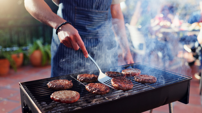 Person in apron grilling burgers