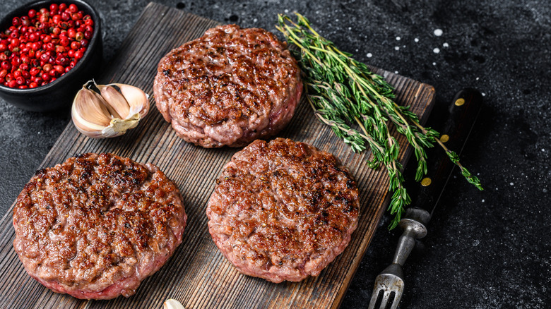 Cooked burgers resting on cutting board