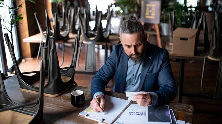 man sitting at table looking at paper and planning