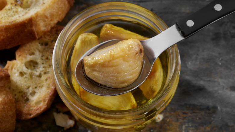 Garlic confit soaking in a jar of olive oil