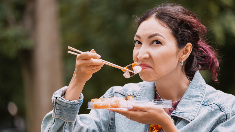 woman grimaces at unpleasant sushi smell