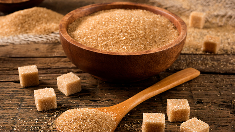 Brown sugar in a wooden bowl and spoon with sugar cubes near