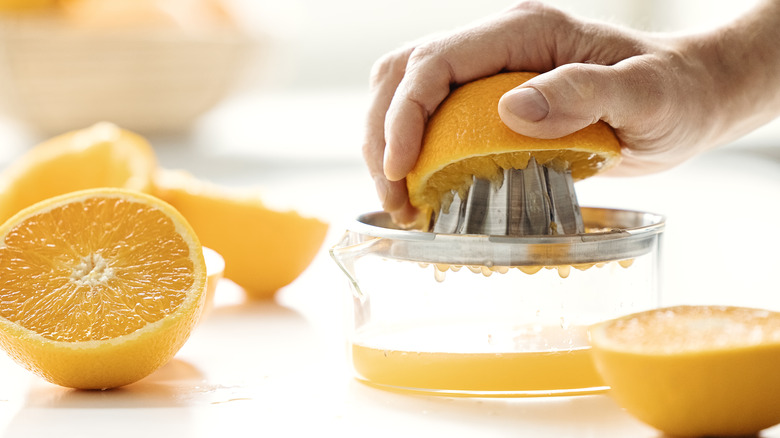 Hand twisting a half orange on a citrus reamer