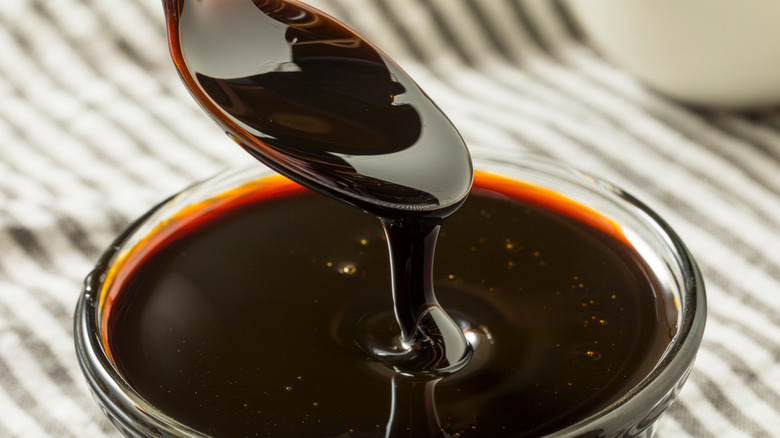 A spoon dipping into bowl of dark, thick molasses