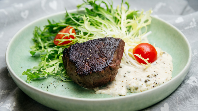 Overcooked steak on plate with garnish