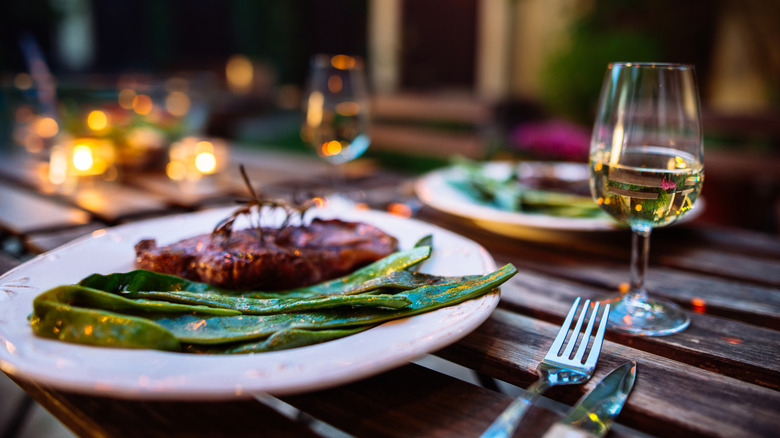 Plated steak served outdoors with white wine