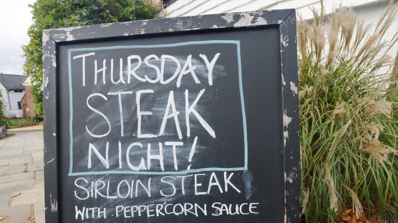 A restaurant chalkboard promoting a steak special