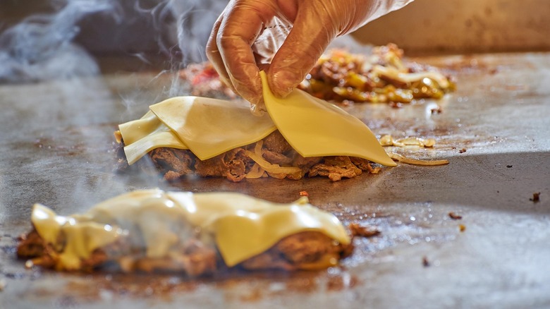 placing cheese onto chicken on grill