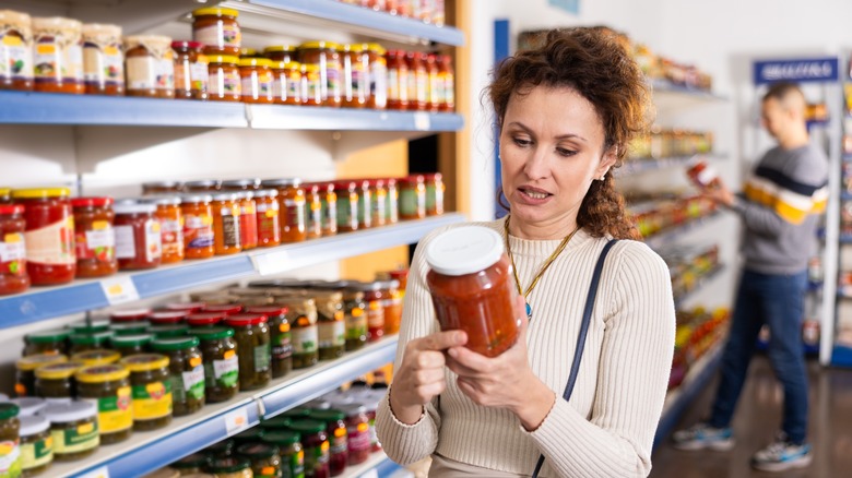 Woman looking at jar of sauce