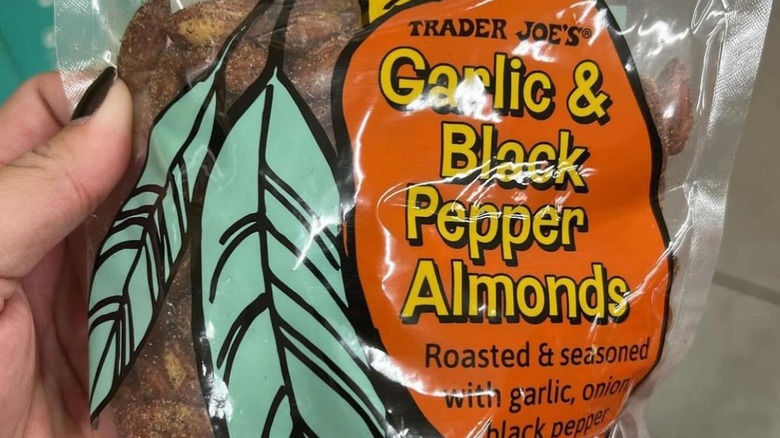 Hand holding up a bag of Trader Joe's Garlic & Black Pepper Almonds