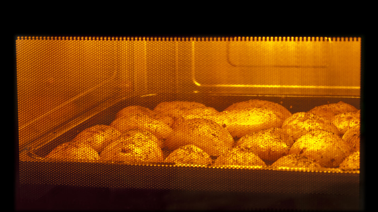 A sheet pan with baking potatoes in oven