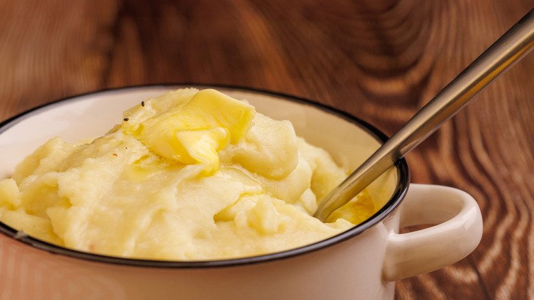 Mashed potatoes in a pot with butter melting on top