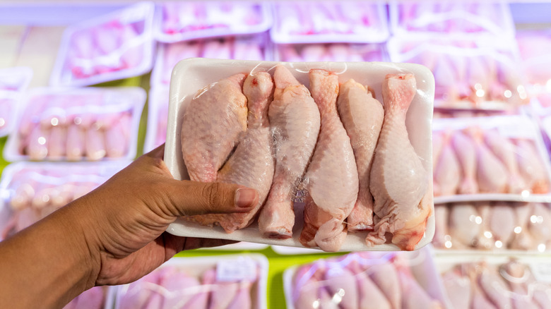 Hand holding packet of chicken at grocery store