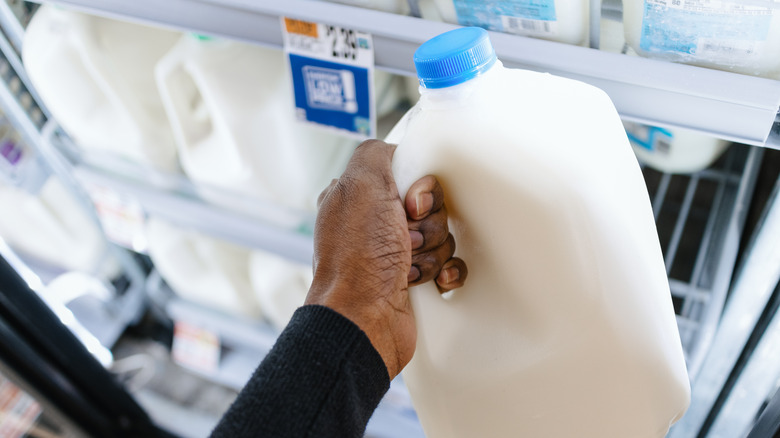 Hand grabbing a gallon of milk at store