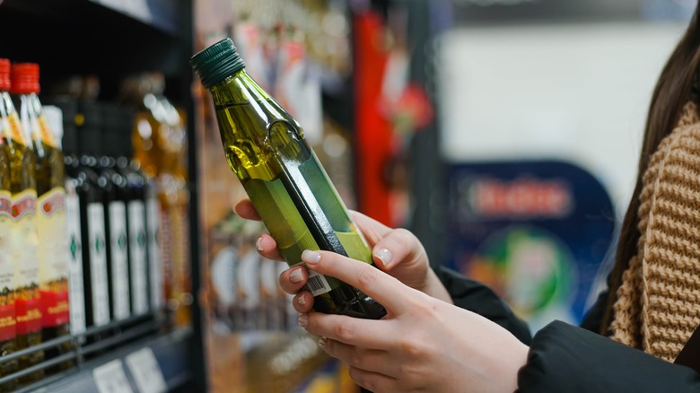 Hands holding olive oil in store