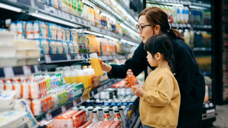 Shopping mother and child picking up orange juice