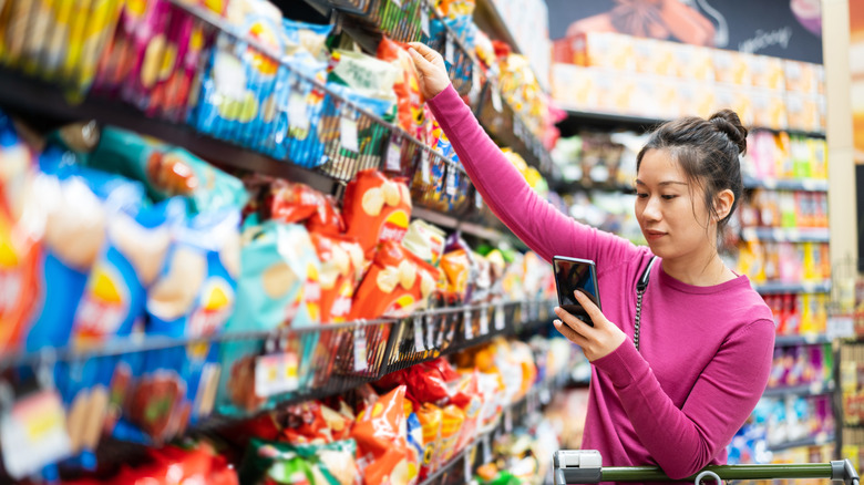 Woman grabbing bag of chips from shelf