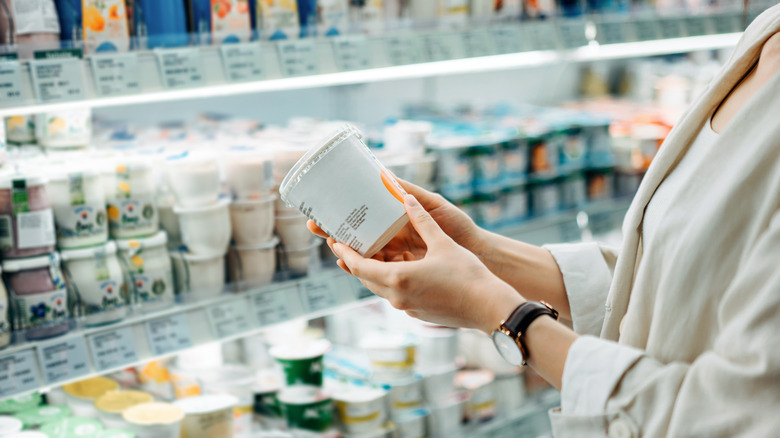 Hands holding yogurt at grocery store