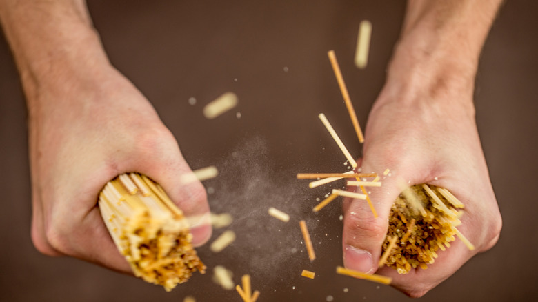 Close-up of hands breaking spaghetti