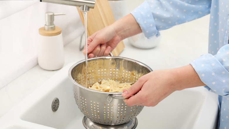 Rinsing pasta in a colander under the faucet