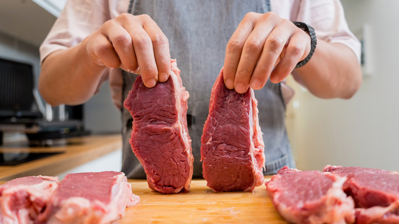 Hands holding two raw steaks