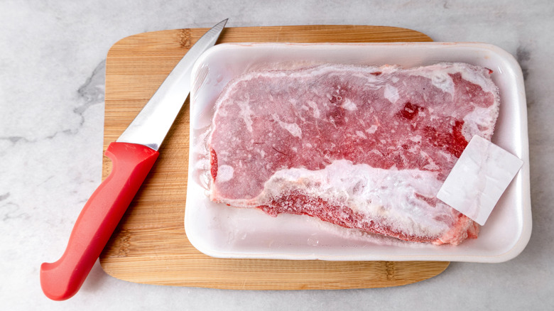 Frozen steak and knife on cutting board