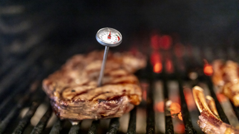 Thermometer in a steak on a grill