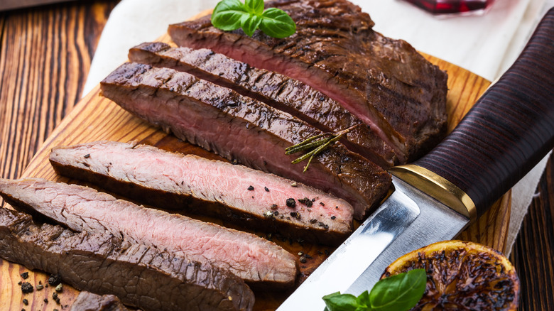 Sliced steak on cutting board with knife