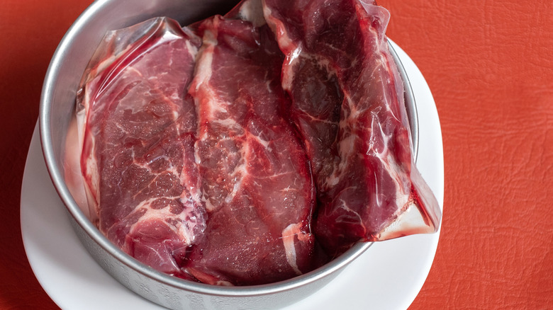 Frozen beef thawing in bowl