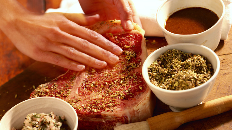 Hand rubbing seasoning on a steak