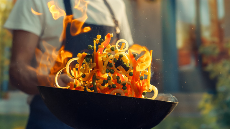 flaming stir fry tossed in air from wok