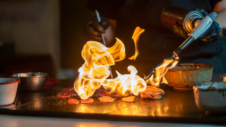 man torching food on grill