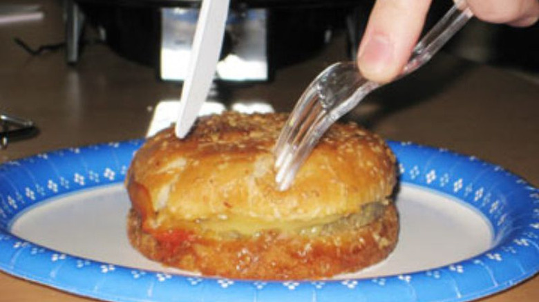 Utensils cutting cheeseburgers from a can