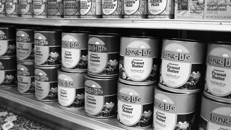 Black and white photo of peanut butter in a can on a grocery shelf