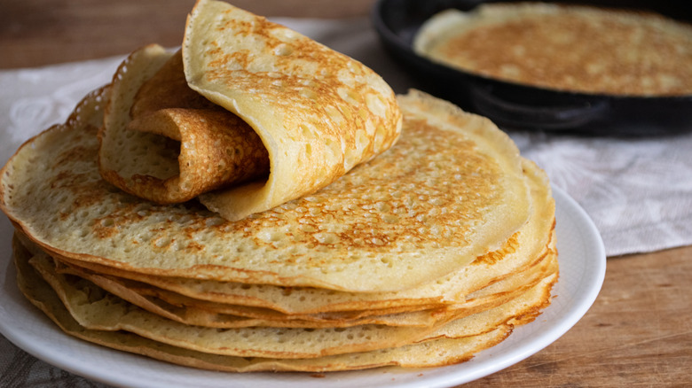 Thin and golden pancakes stacked on plate