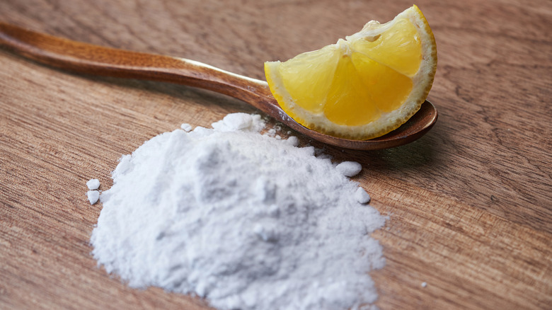 Baking soda on wooden table with spoon and lemon