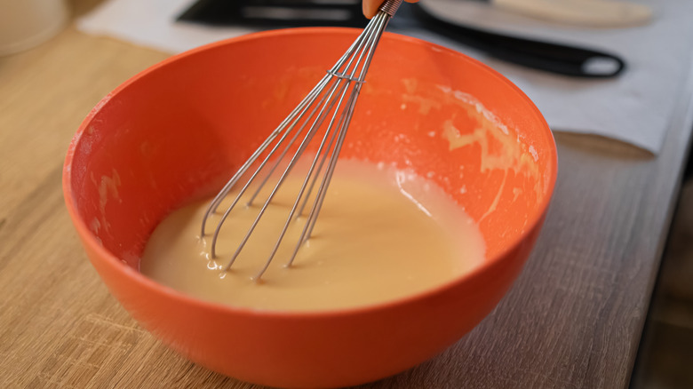 Whisking pancake batter in orange bowl