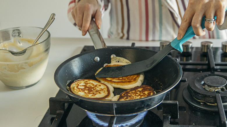 Person pressing down on pancakes