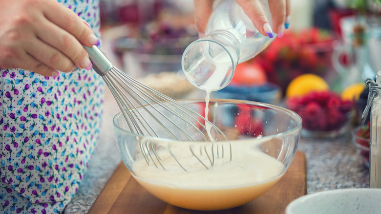 Person pouring milk into pancake batter