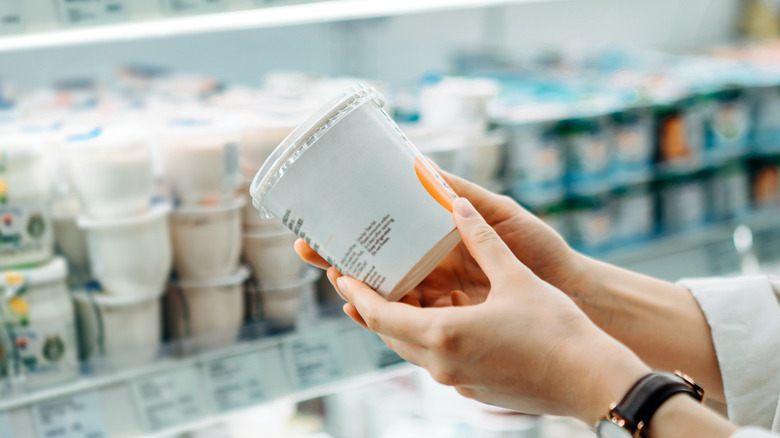 Person inspecting yogurt in grocery store