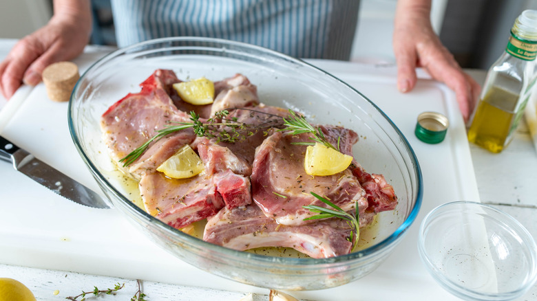 Pork chops in a bowl of marinade on a cutting board