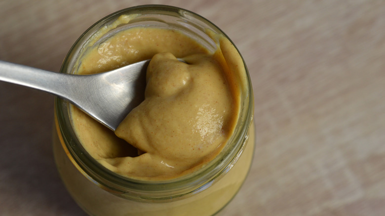 Spoon in a jar of Dijon mustard