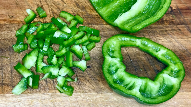 Sliced and diced green peppers on a wooden chopping board